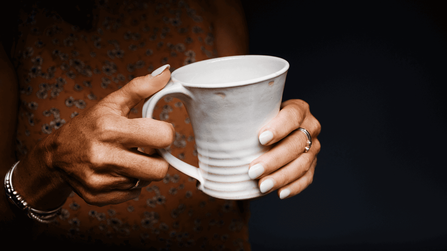 A woman holding a freshly made cup of coffee with both her hands