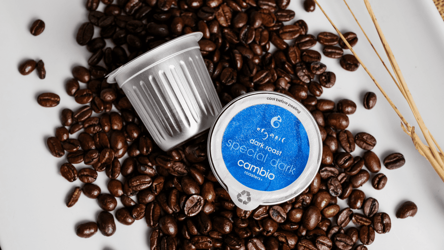 Aluminum coffee pods on top of a bunch of coffee beans