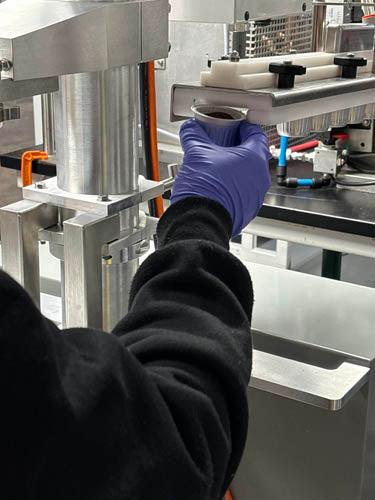 person closing the lid on an aluminum coffee pod