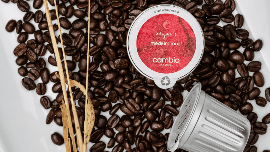 A cambio aluminum coffee pod sitting on some coffee beans