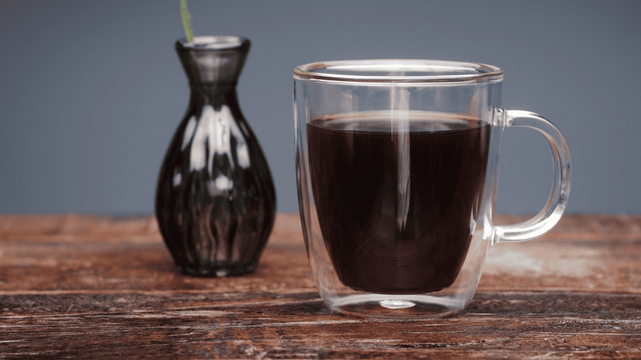 A table with a see-through mug of coffee
