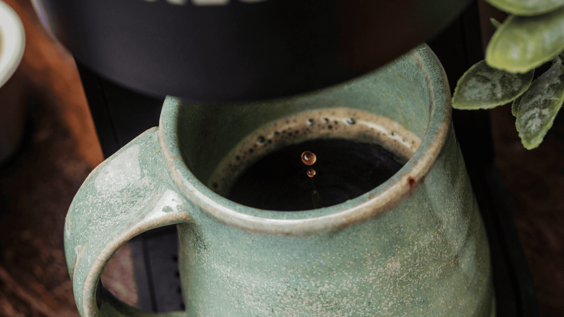 A mug being filled up with freshly brewed coffee