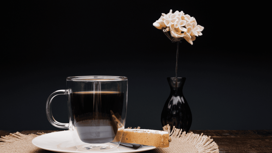 coffee mug with coffee and a piece of bread next to it