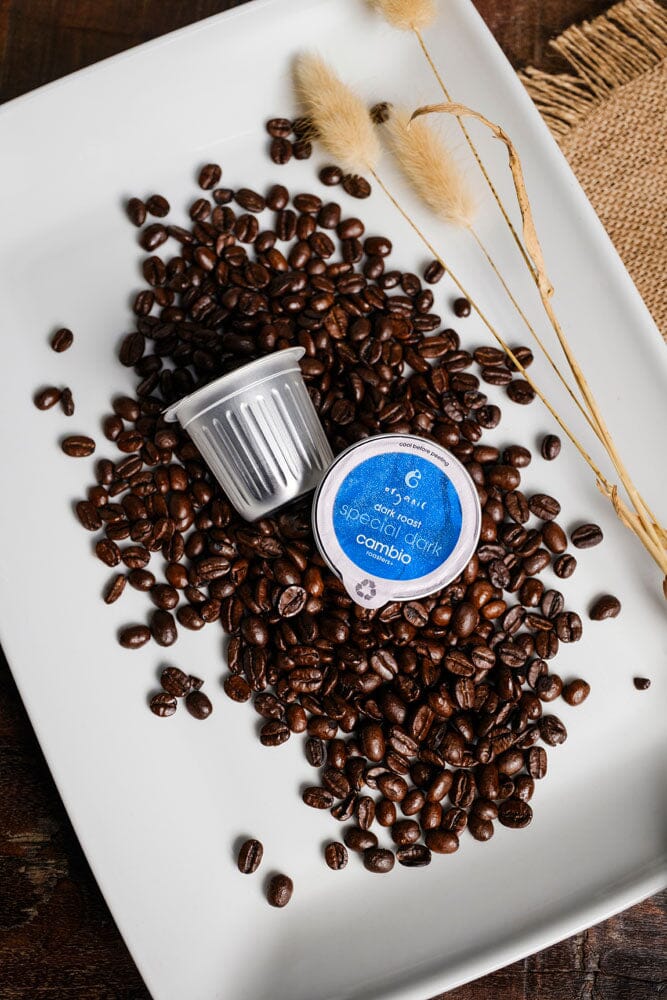 a plate with a bunch of coffee beans and aluminum coffee pods