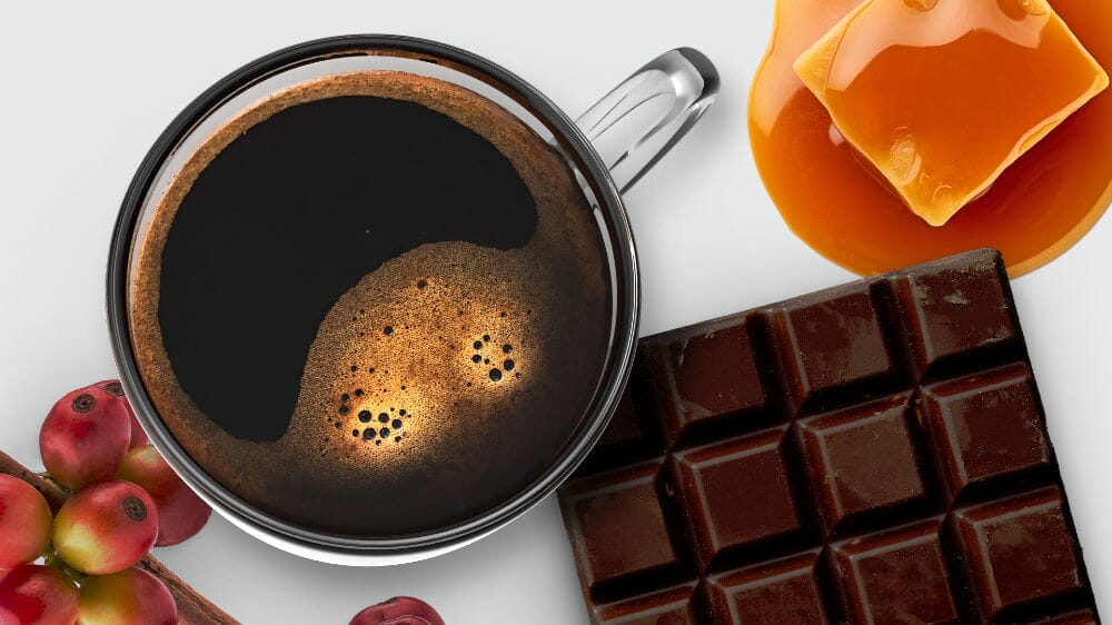 Cup of coffee with chocolate bars, caramel, and coffee beans on a white background