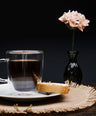 a clear mug of coffee with a piece of bread